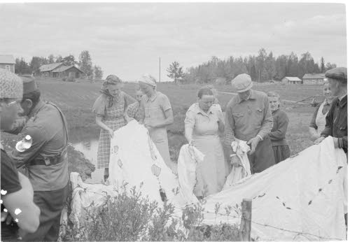 Siviiliväkeä tutkimassa laskuvarjon jäännöksiä